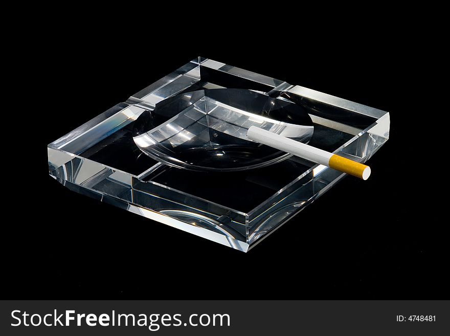 A crystalline ashtray and a cigarette. A crystalline ashtray and a cigarette