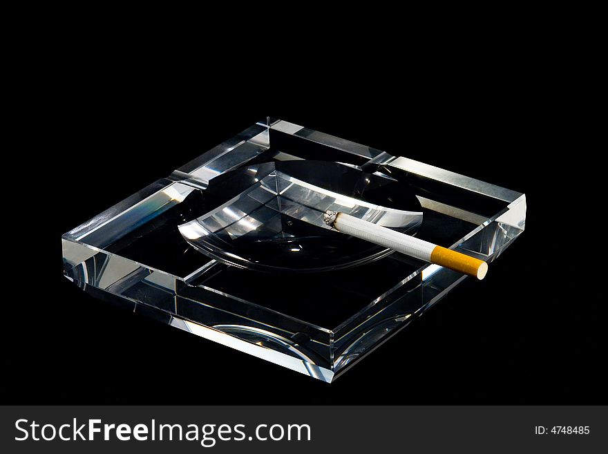 A crystalline ashtray and a cigarette. A crystalline ashtray and a cigarette