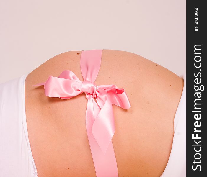 A pregnant belly with a pink gift wrap on the side. A pregnant belly with a pink gift wrap on the side