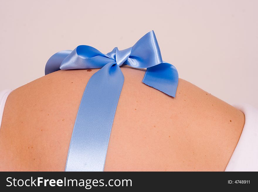 A pregnant belly with a blue gift wrap. A pregnant belly with a blue gift wrap