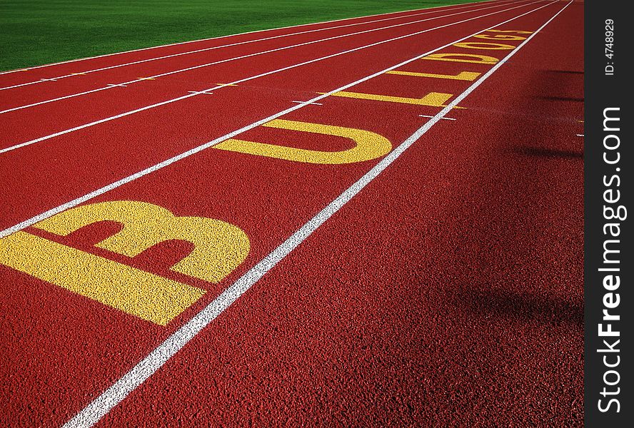 Shot of a black surfaced running track showing the lane markers of one through four and a grass covered infield. Shot of a black surfaced running track showing the lane markers of one through four and a grass covered infield.