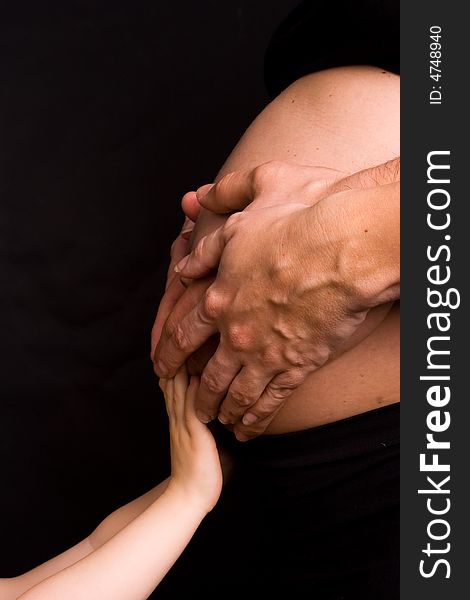 Hands of parents and child on pregnant belly