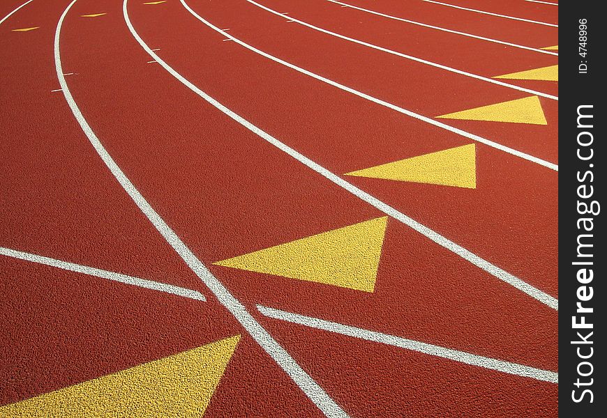 Shot of a black surfaced running track showing the lane markers of one through four and a grass covered infield. Shot of a black surfaced running track showing the lane markers of one through four and a grass covered infield.