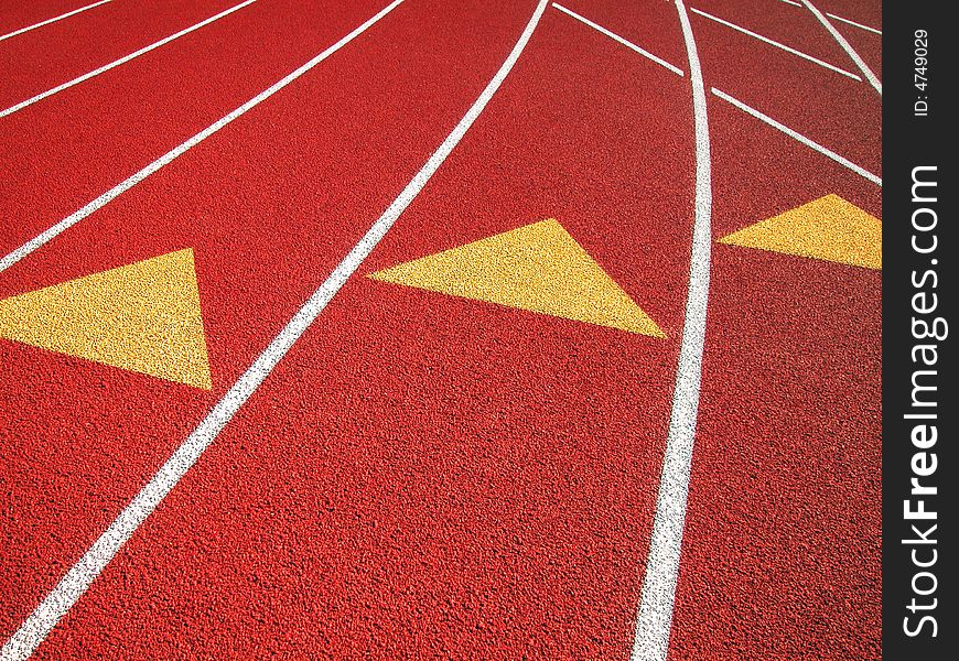 Shot of a black surfaced running track showing the lane markers of one through four and a grass covered infield. Shot of a black surfaced running track showing the lane markers of one through four and a grass covered infield.