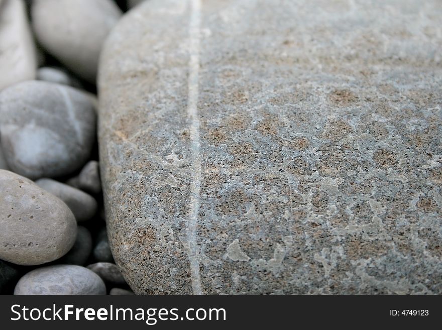 Grey pebbles background, a big one with a white stripe and several small ones