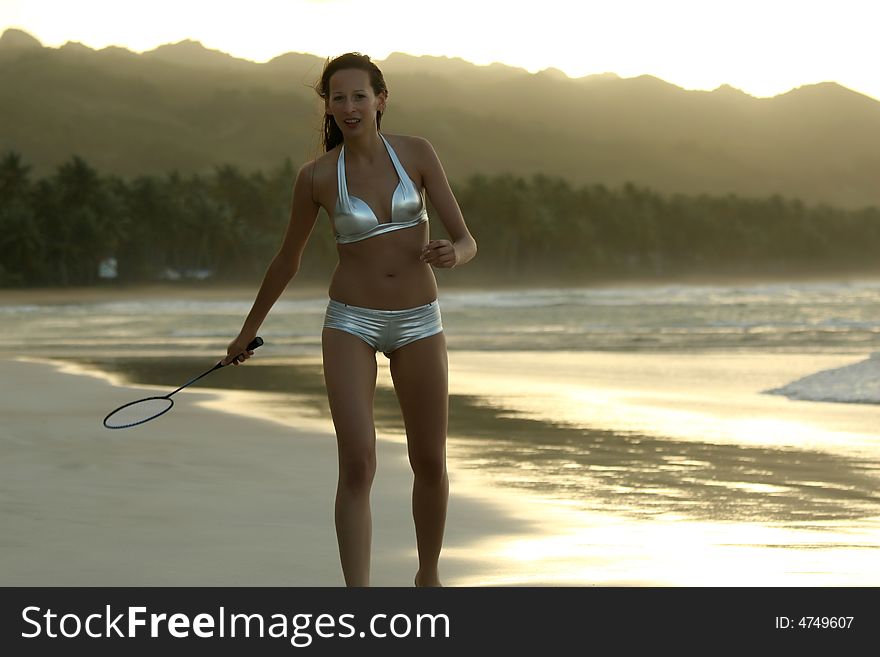 Woman in bikini plays badminton on the beach. Woman in bikini plays badminton on the beach