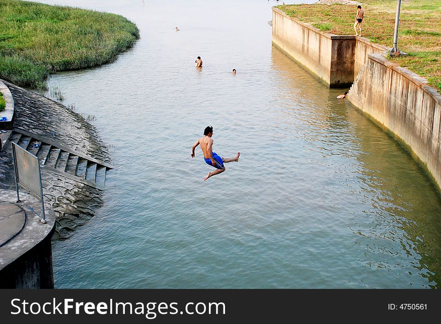 A young man jumping into a river by the village in a hot summer afternoon,Foshan,Guangdong,China,Asia. A young man jumping into a river by the village in a hot summer afternoon,Foshan,Guangdong,China,Asia.