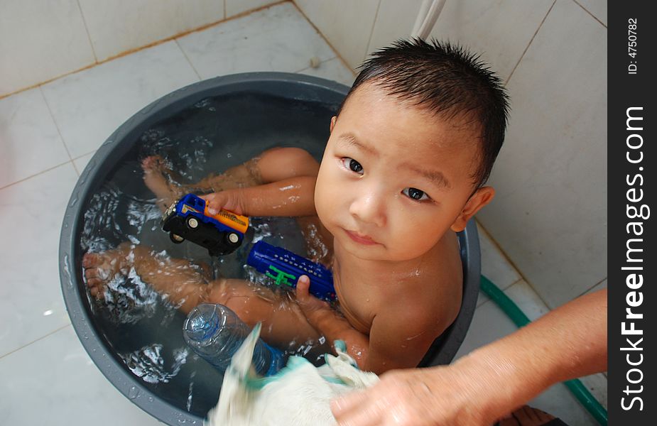 A little chinese boy is having a bath in a big basin. A little chinese boy is having a bath in a big basin.