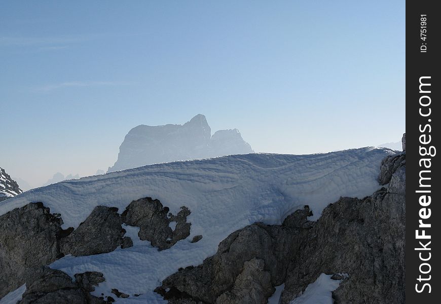 Dolomite rock covered with snow and Pelmo peak in  the background. Dolomite rock covered with snow and Pelmo peak in  the background