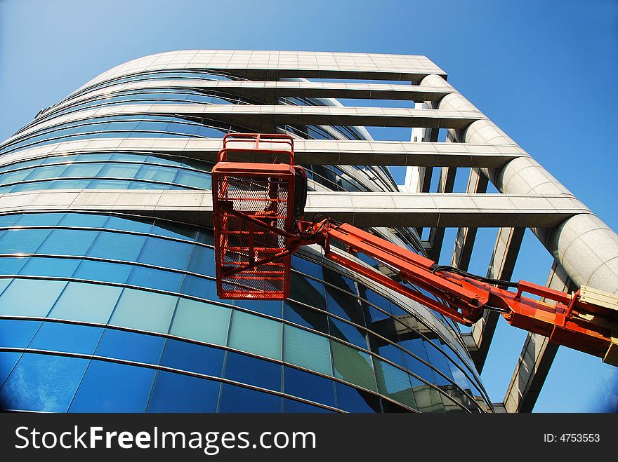 Huge glass building with crane & blue sky