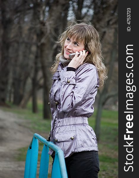 Girl speaks by phone in park. Girl speaks by phone in park