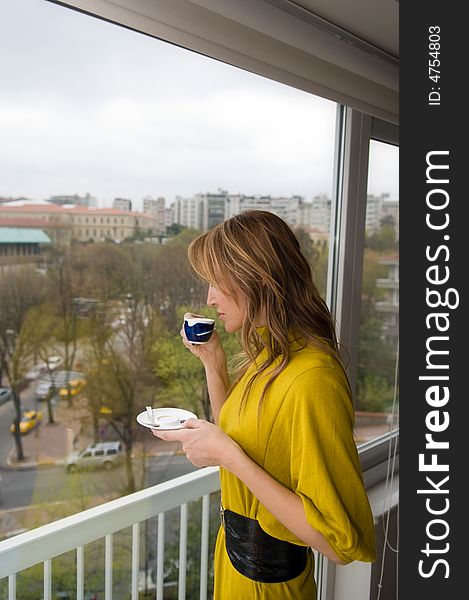 A women is tasting coffee by a window. A women is tasting coffee by a window