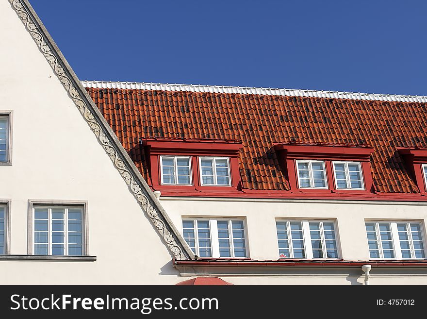 White house with windows with tiled roof and blue sky at sunny day to Old Town Tallinn. White house with windows with tiled roof and blue sky at sunny day to Old Town Tallinn