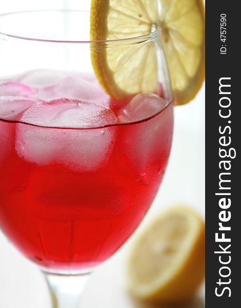 Red cocktail drink with ice and lemon