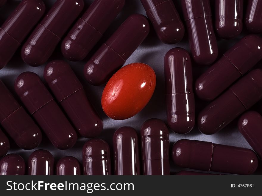 A lot of same capsules with red pill in the middle. A lot of same capsules with red pill in the middle