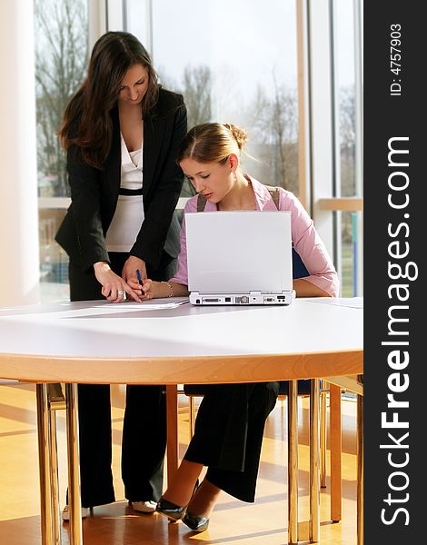 A successful business woman and her secretary with a document on a table with a laptop