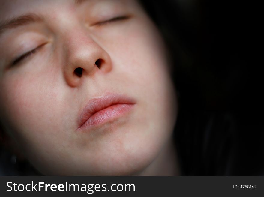 A detail of sleeping woman face isolated on a black background