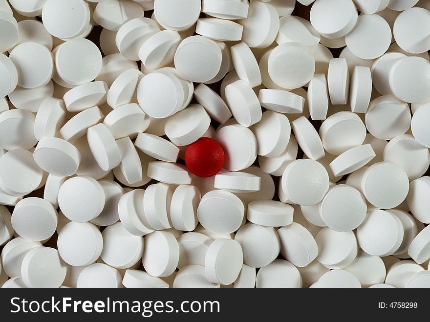 A lot of white pills with red pill in the middle. A lot of white pills with red pill in the middle