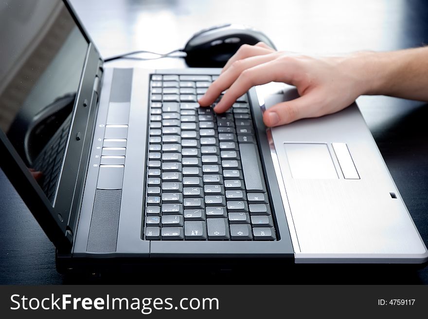 Male hand pushing the enter button on a laptop keyboard. Hand is out of focus!