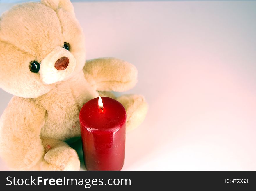 A teddy bear and a burning candle in one corner. A teddy bear and a burning candle in one corner