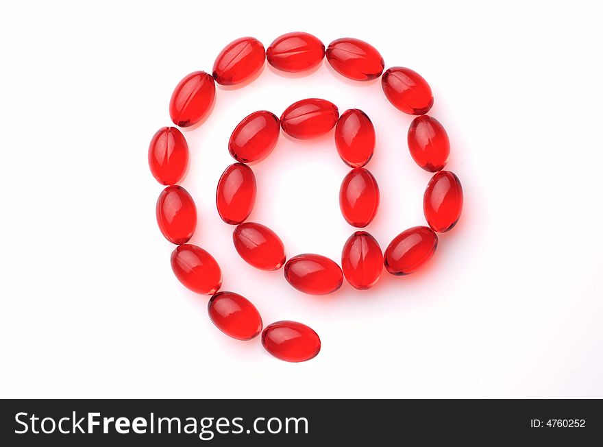 At symbol made of red capsules on white background
