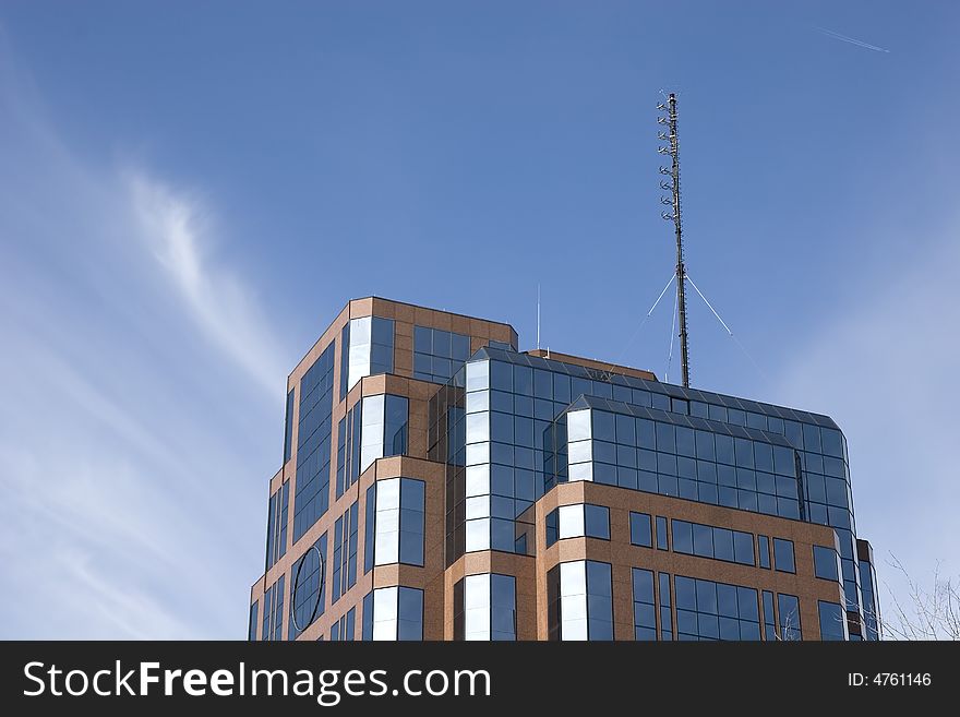 A nice brick and glass office building rising into a blue sky and puffy clouds. A nice brick and glass office building rising into a blue sky and puffy clouds