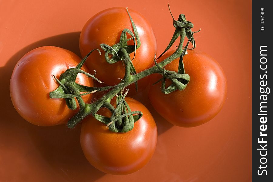 Four tomatoes in a red plate