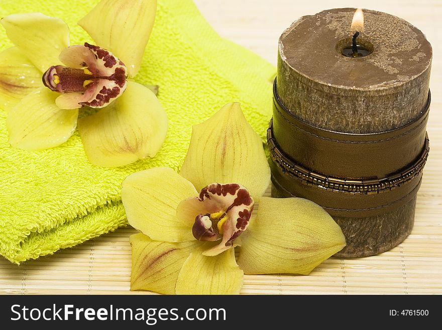 Spa essentials, candle with yellow orchids and towel