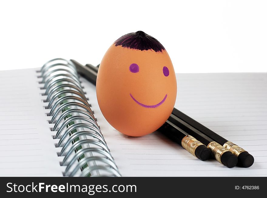 Smiley Egg with unsharpened black pencils on a note book