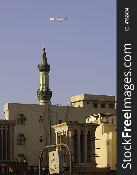 United Arab Emirates: Dubai ; mosque in deira, the old district of the city and a aircraft crossing the blue sky. United Arab Emirates: Dubai ; mosque in deira, the old district of the city and a aircraft crossing the blue sky