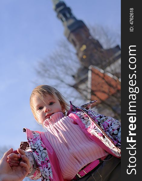 Ittle girl at the background of blue spring sky looking down on photographer or audience. Ittle girl at the background of blue spring sky looking down on photographer or audience