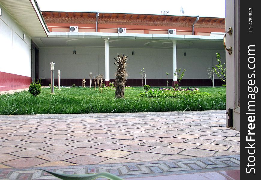 Green grass, wall with pillars on courtyard. Green grass, wall with pillars on courtyard