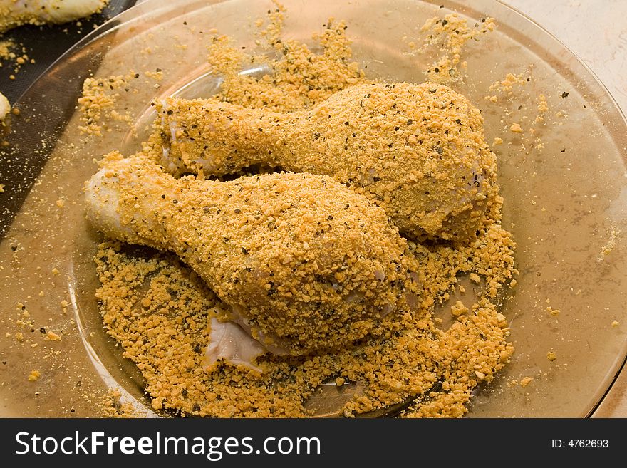 Coated raw chicken drumsticks on the plate