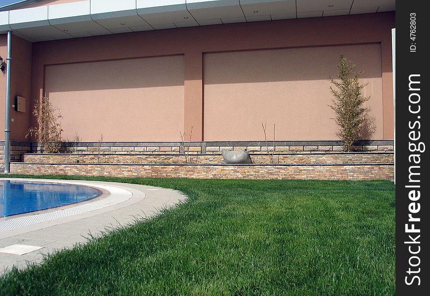 Green grass, cream-coloured wall and pool on courtyard. Green grass, cream-coloured wall and pool on courtyard