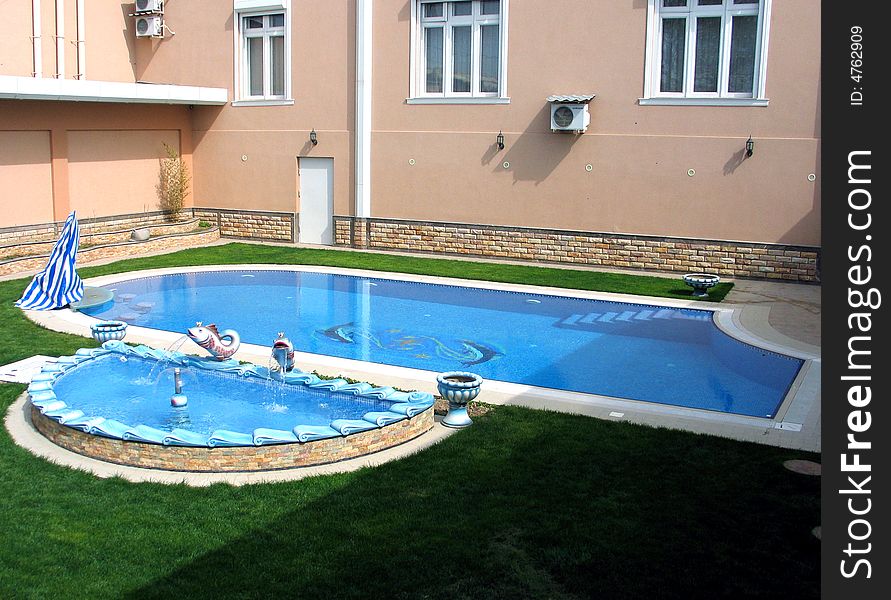 Green grass, cream-coloured wall and pool on courtyard. Green grass, cream-coloured wall and pool on courtyard