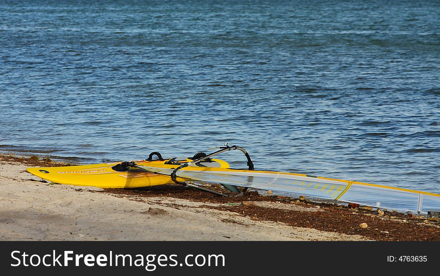 Windsurfer laying on the beach shore abandoned and unused. Windsurfer laying on the beach shore abandoned and unused.