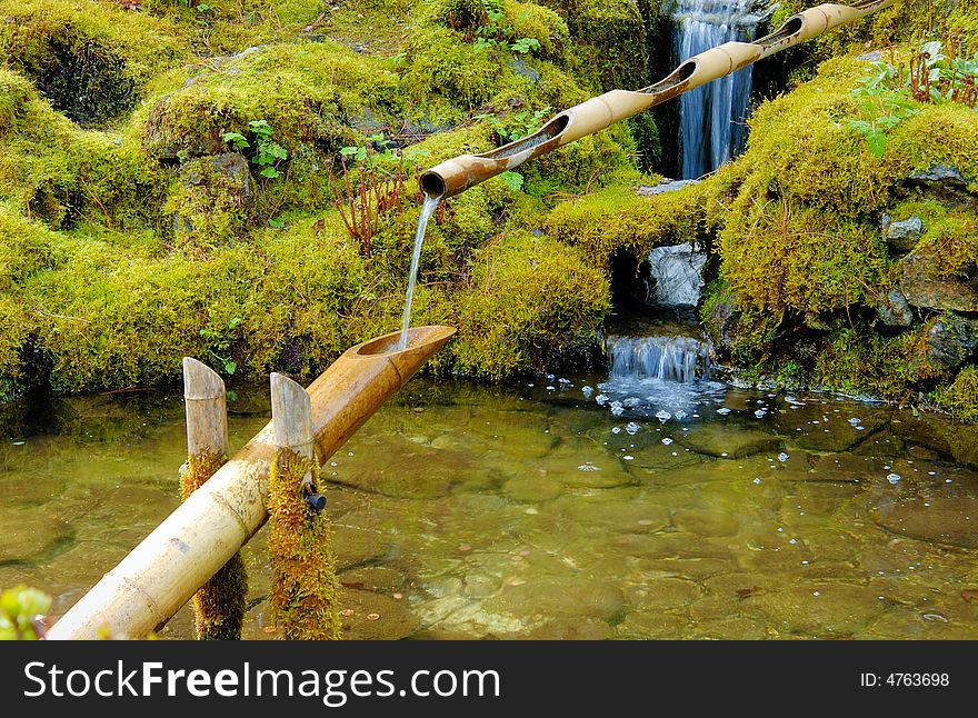 Wooden pipe in the pond in Japanese garden