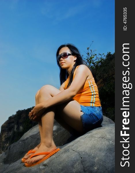 Asian woman on rock by the beach