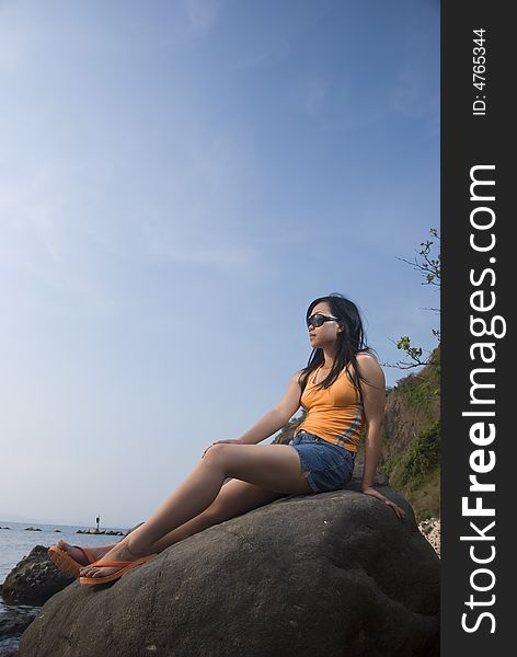 Asian woman on rock by the beach