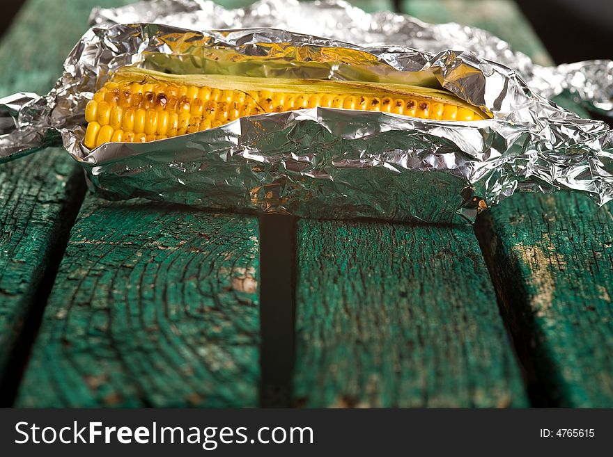 Sweetcorn wrapped in foil on a green bench