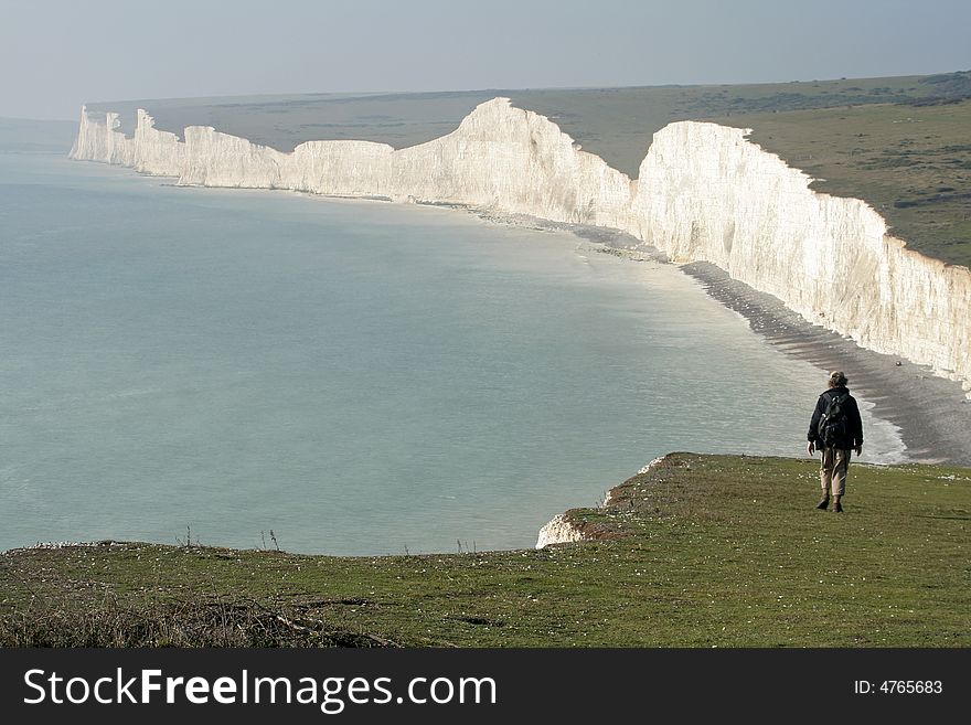 Lone walker takes in the view of the famous Seven Sisters cliffs on Sussex coast. Lone walker takes in the view of the famous Seven Sisters cliffs on Sussex coast