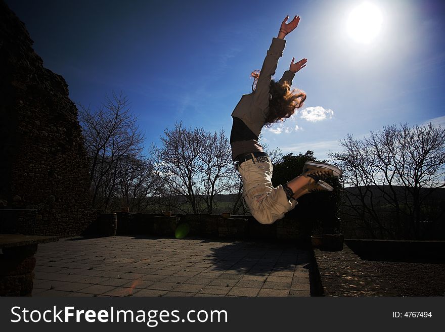 A girl jumping before bright sunny blue sky. A girl jumping before bright sunny blue sky