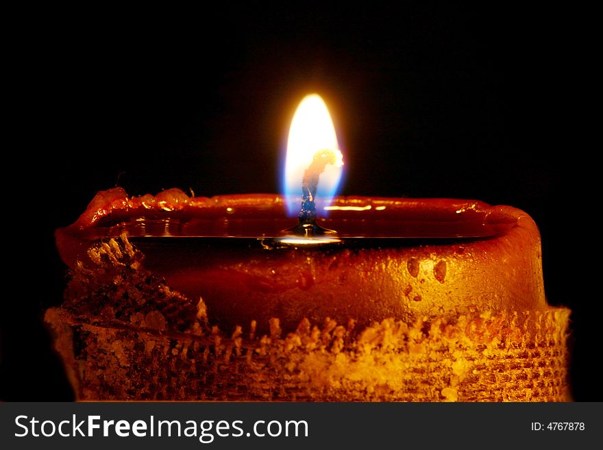 Close up shot of isolated on black glowing candle. Black background. Macro shot, combied from 3 shots to achieve bigger depth of field.