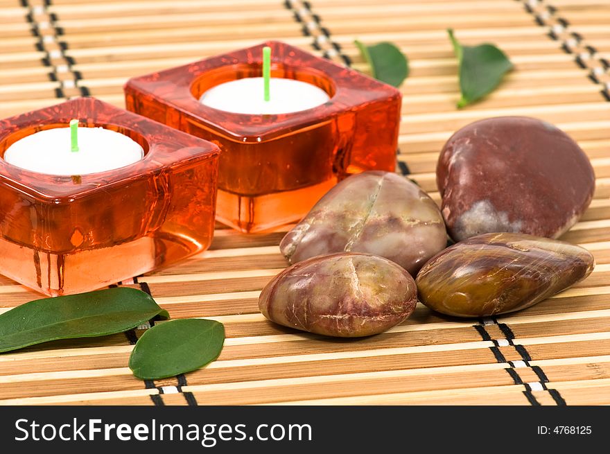 Spa stones, candles and green leaves on bamboo. Spa stones, candles and green leaves on bamboo