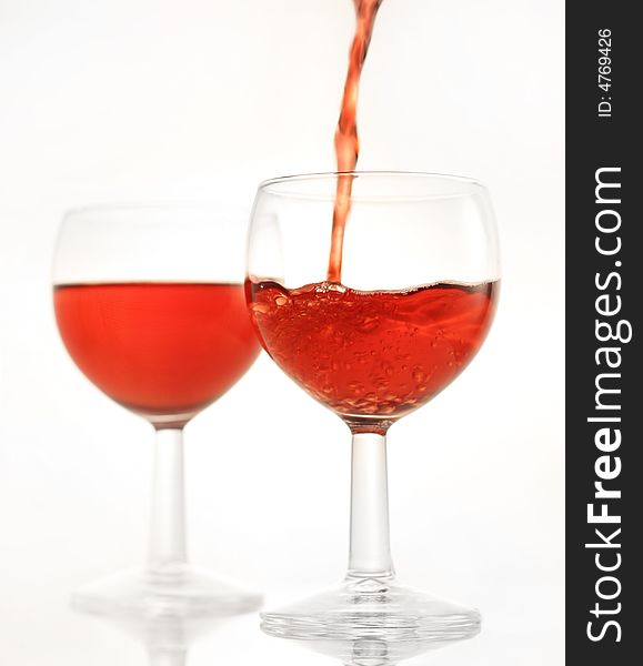 Pouring a red wine in to a glass, another filled up glass in the background, shallow depth of field, please check for more. Pouring a red wine in to a glass, another filled up glass in the background, shallow depth of field, please check for more