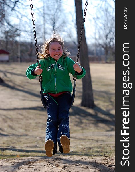 A pretty smiling blonde girl mid-air on a swing. A pretty smiling blonde girl mid-air on a swing.