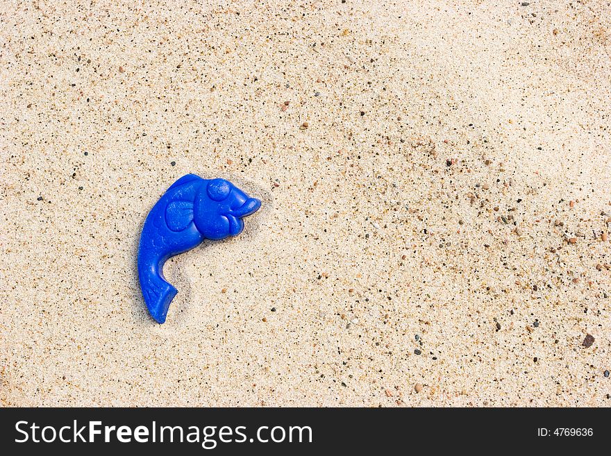 Lost toy fish on a sandy beach