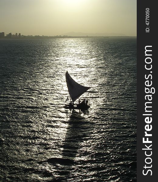 A sail boat silhouette and reflection.