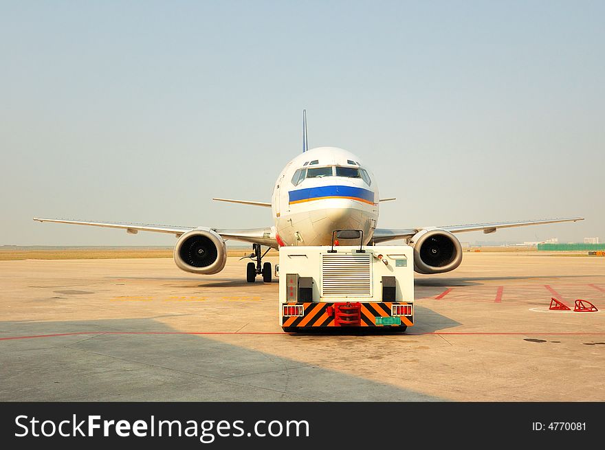 Traction aircraft equipment is pushing the plane took off at the airport runway. Traction aircraft equipment is pushing the plane took off at the airport runway