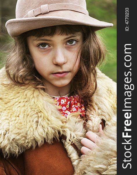 Little sad girl wearing a hat and vintage winter fur coat. Little sad girl wearing a hat and vintage winter fur coat